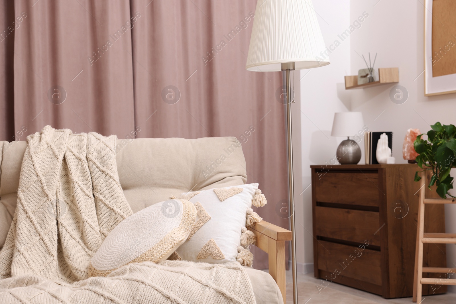 Photo of Comfortable sofa, cushions and blanket in cozy room. Interior design