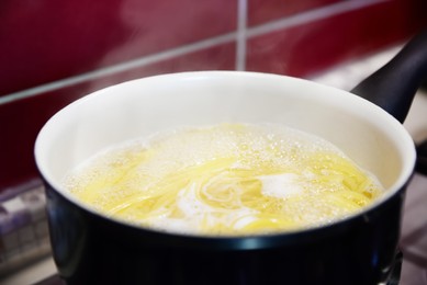 Cooking pasta in saucepan on stove, closeup