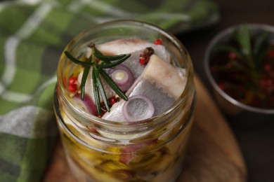 Tasty marinated fish with onion and rosemary in jar on table, closeup