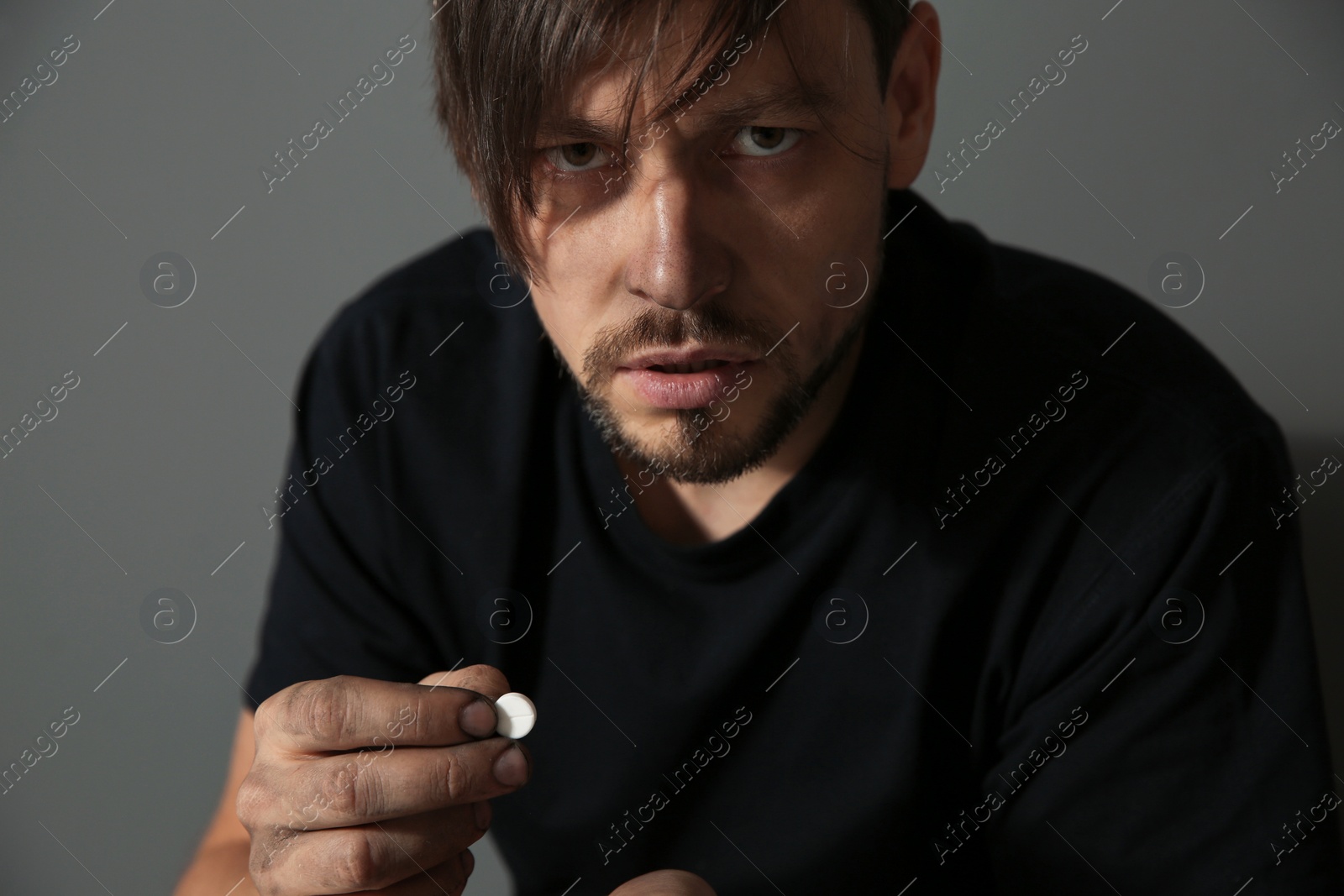 Photo of Young addicted man with drugs on grey background