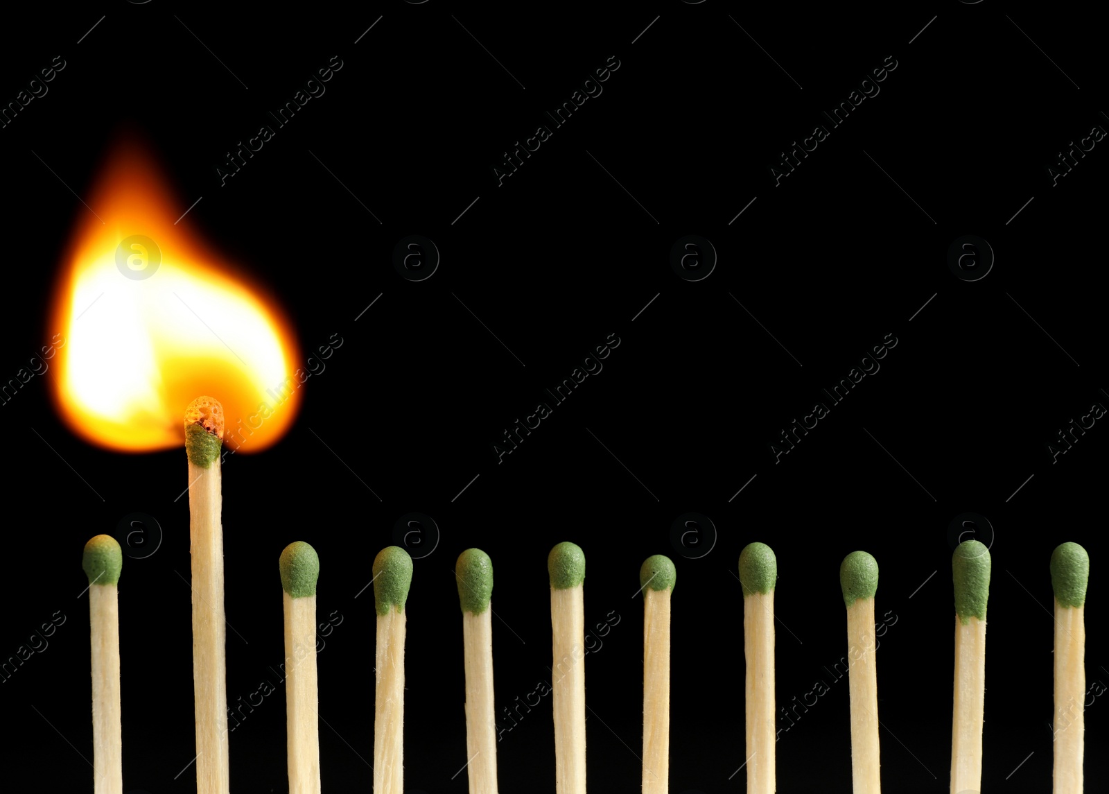 Photo of Burning match among unlit ones on black background, closeup