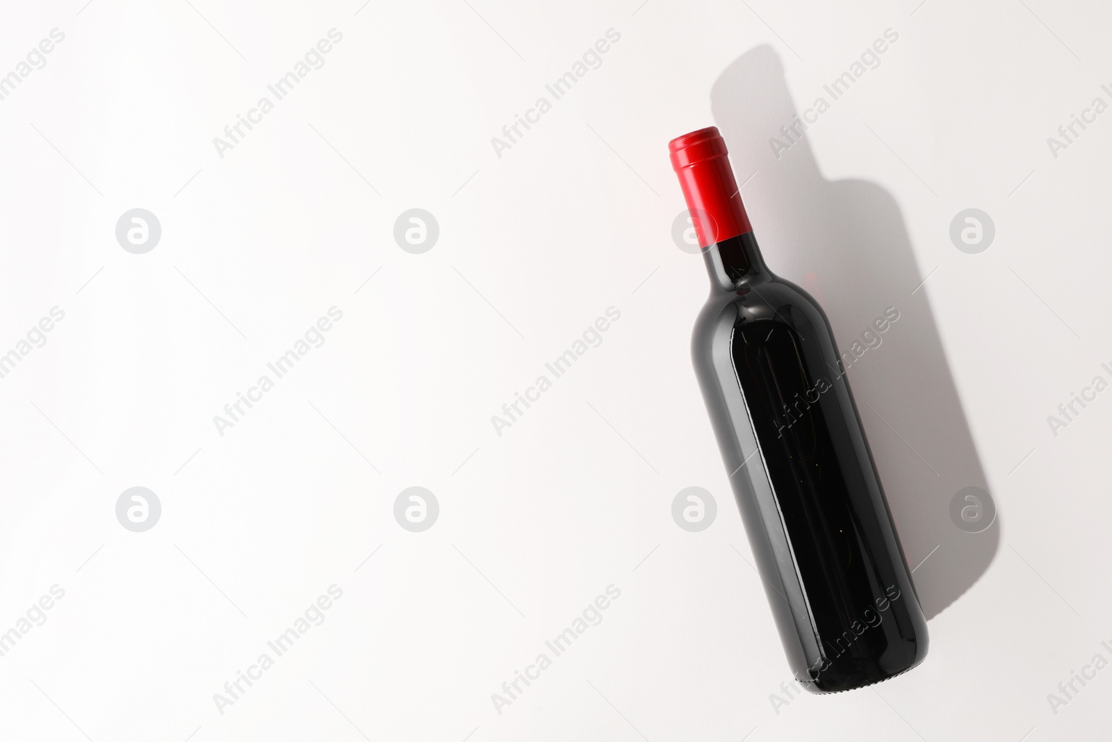 Photo of Bottle of expensive red wine on white background, top view. Space for text