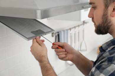 Photo of Man repairing modern cooker hood indoors, closeup