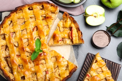 Photo of Traditional apple pie and ingredients on light grey table, flat lay