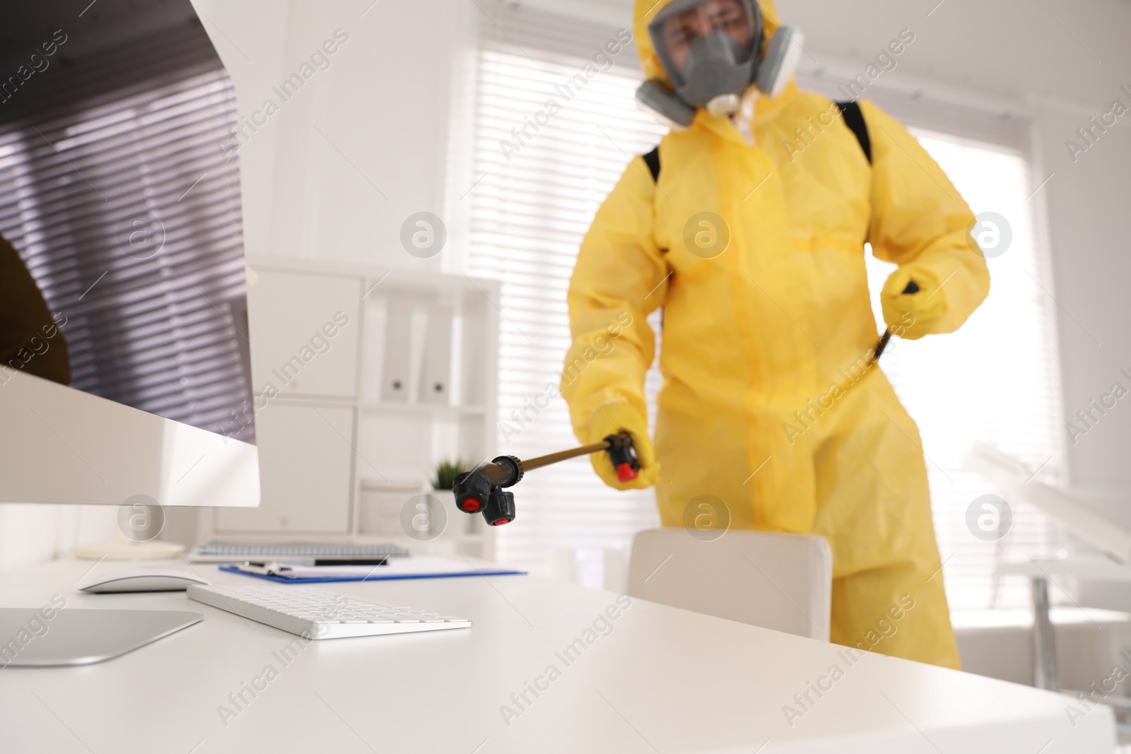 Photo of Man in protective suit sanitizing doctor's office. Medical disinfection