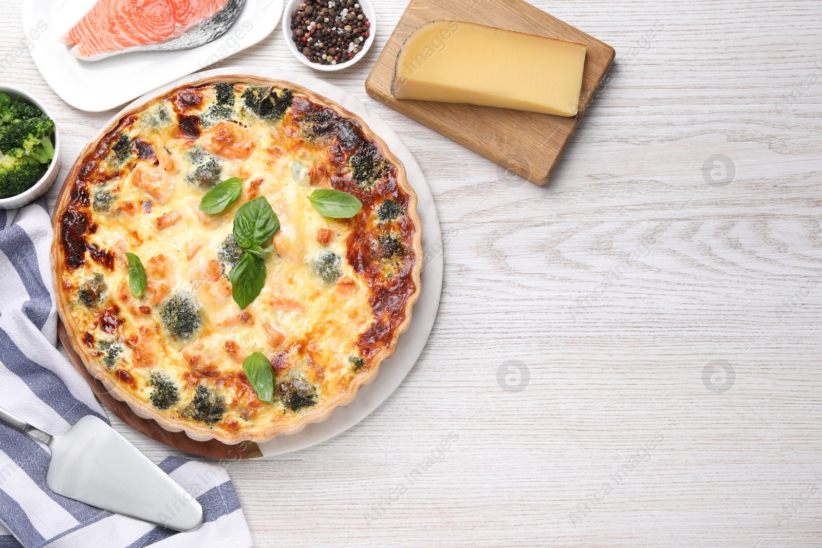 Photo of Delicious homemade quiche and ingredients on wooden table, flat lay. Space for text