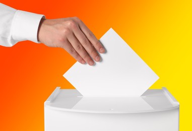 Man putting his vote into ballot box on color background, closeup