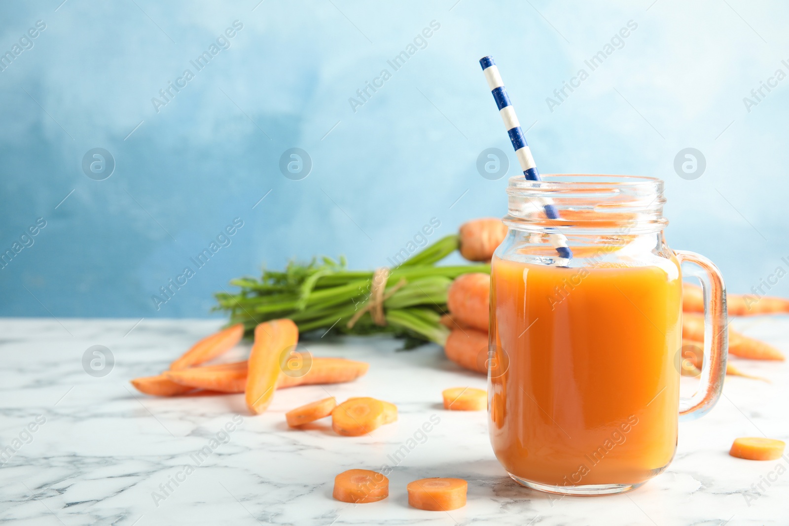 Photo of Mason jar with carrot juice and fresh vegetable on table