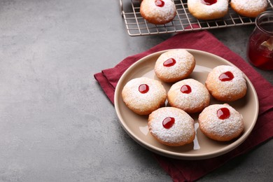 Hanukkah donuts with jelly and powdered sugar on grey table, space for text