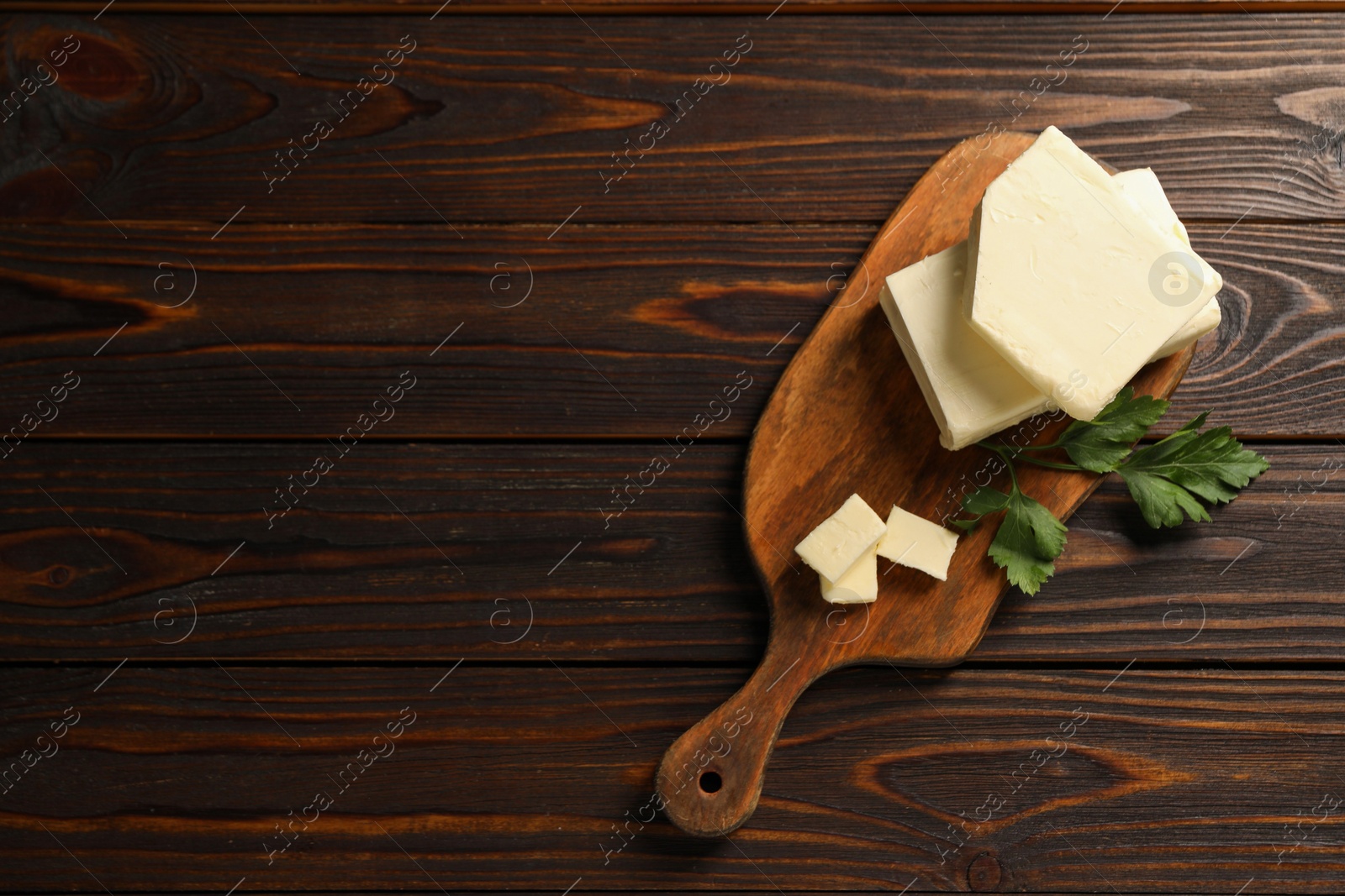 Photo of Tasty butter and parsley on wooden table, top view. Space for text