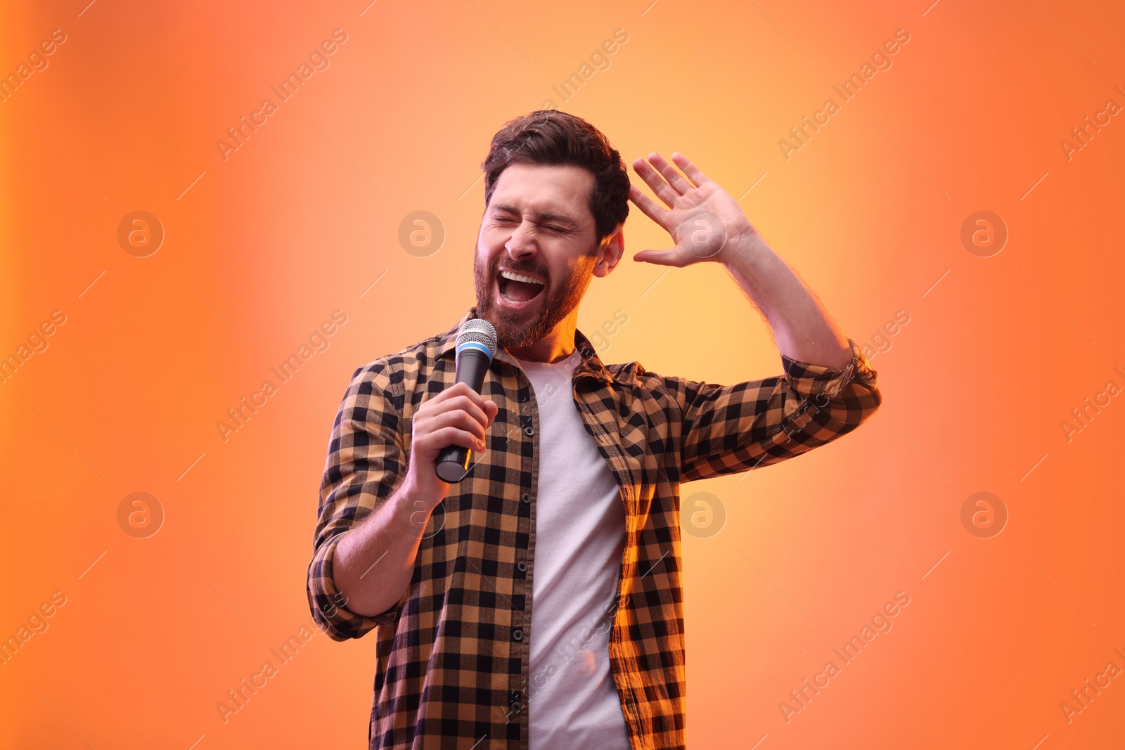 Photo of Handsome man with microphone singing in color lights