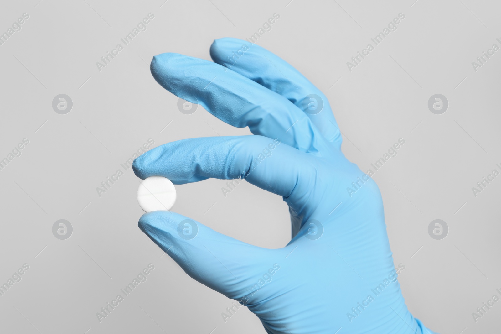 Photo of Doctor holding pill on grey background, closeup