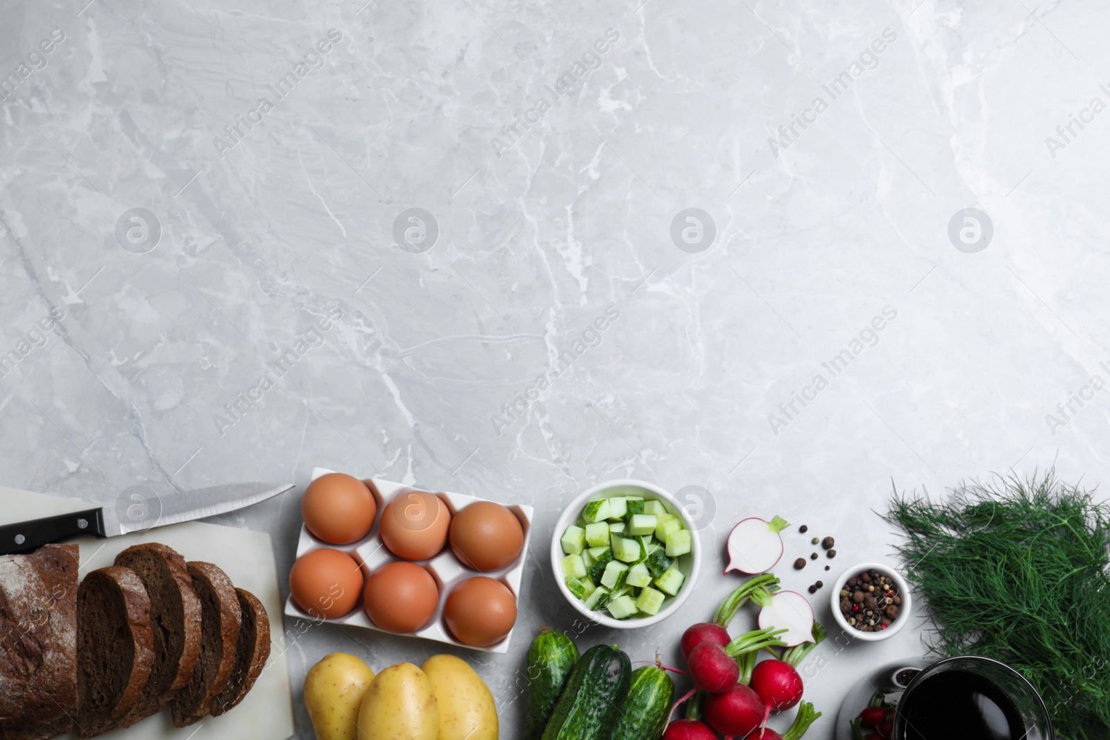 Photo of Flat lay composition with kvass and other okroshka ingredients on grey table, space for text. Traditional Russian summer soup