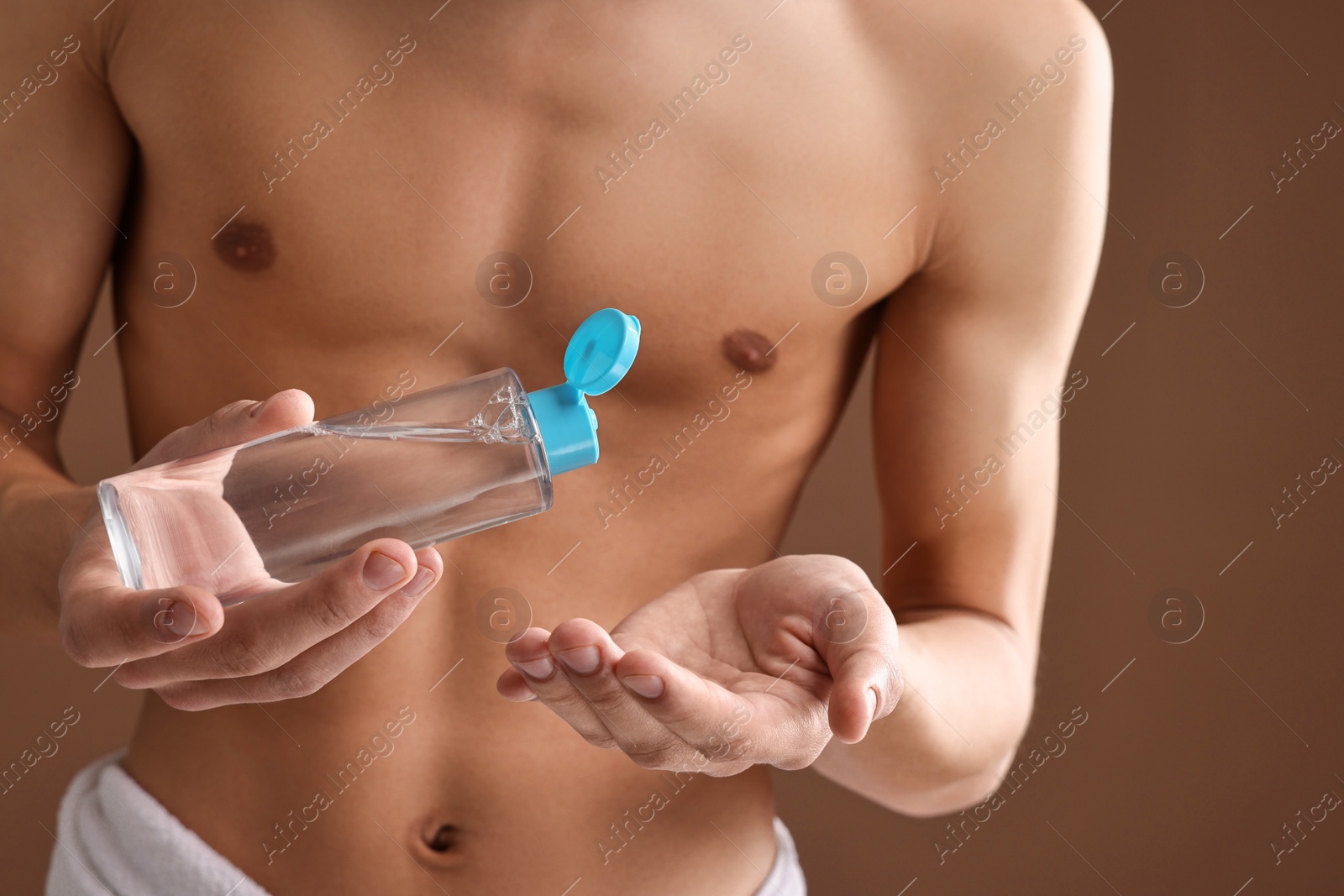 Photo of Man with body lotion on brown background, closeup