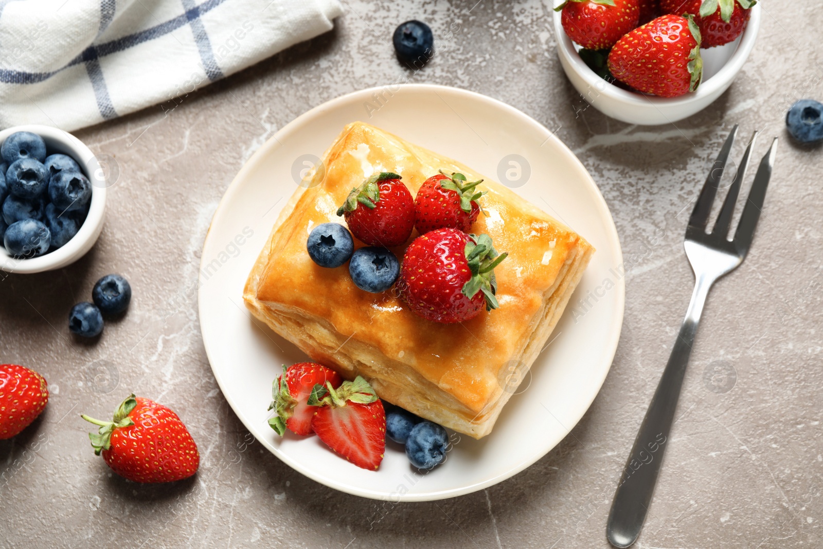 Photo of Fresh delicious puff pastry with sweet berries on grey marble table, flat lay