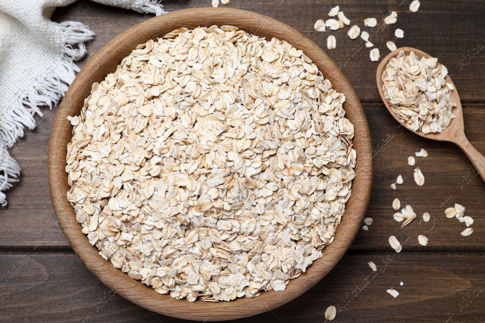 Photo of Bowl and spoon with oatmeal on wooden table, flat lay