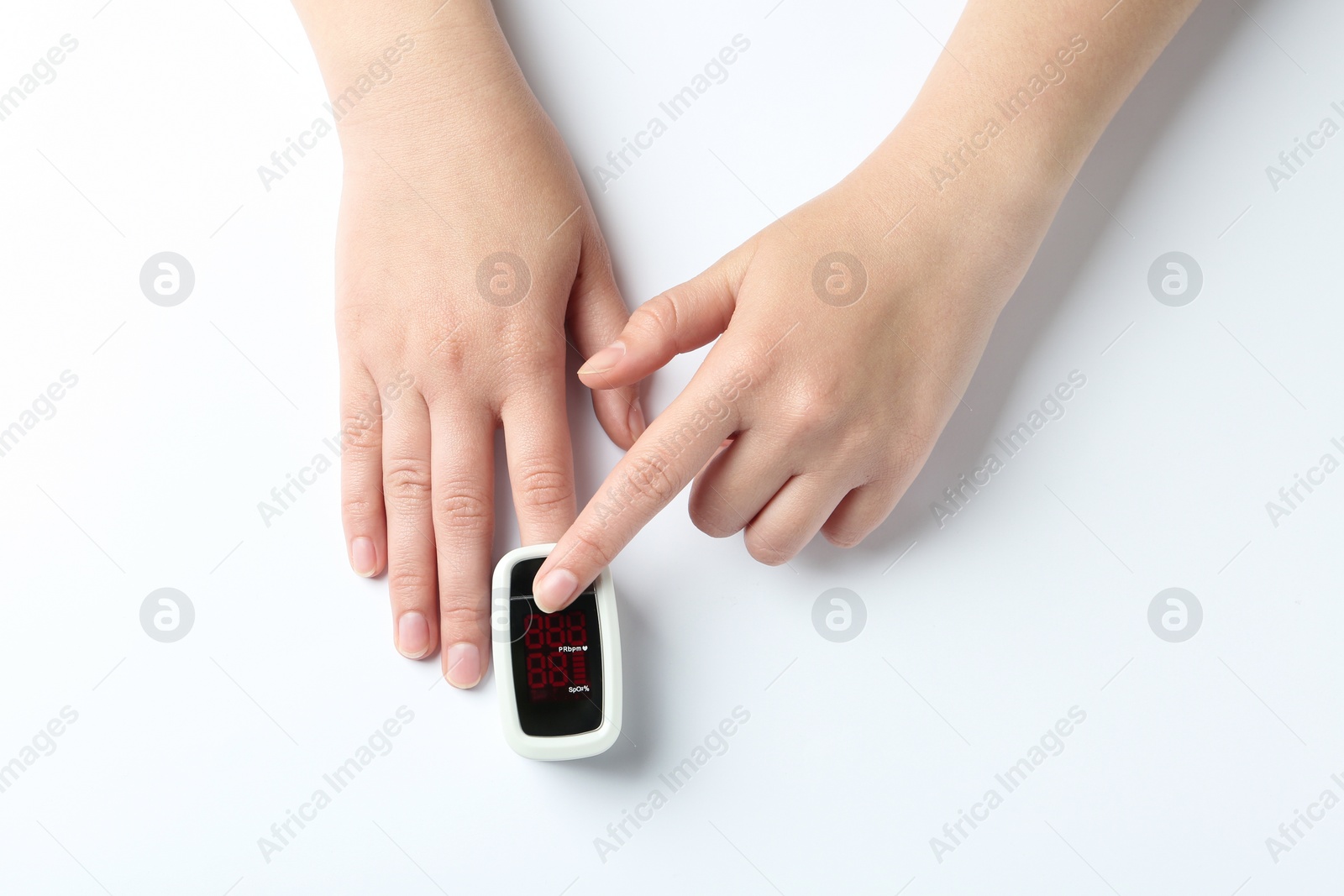 Photo of Woman using fingertip pulse oximeter on white background, top view