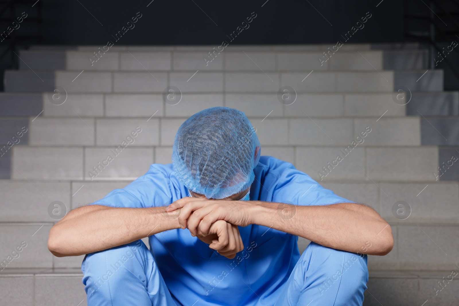 Photo of Exhausted doctor sitting on stairs in hospital