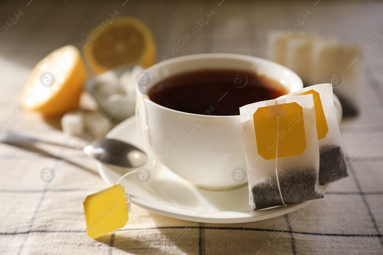 Photo of Tea bags near cup of hot drink on table, closeup