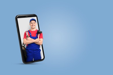 Image of Plumber looking out of smartphone on light blue background. Space for text