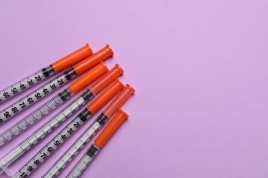 Disposable syringes on violet background, flat lay. Space for text