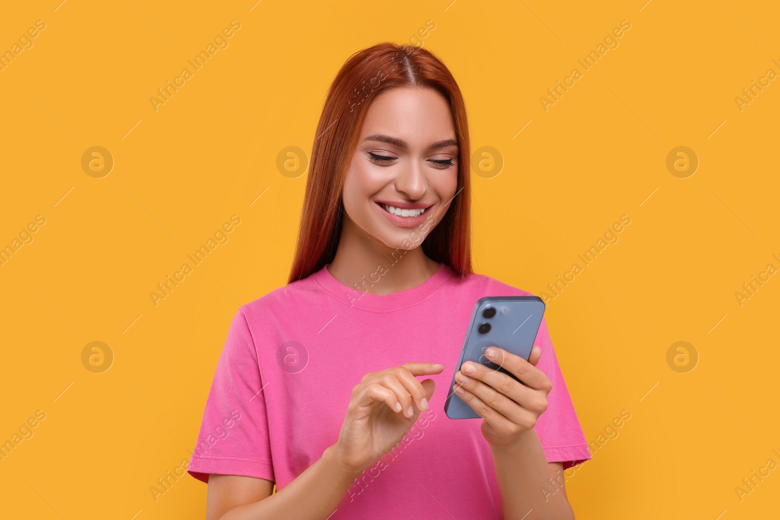 Photo of Beautiful happy woman using smartphone on orange background