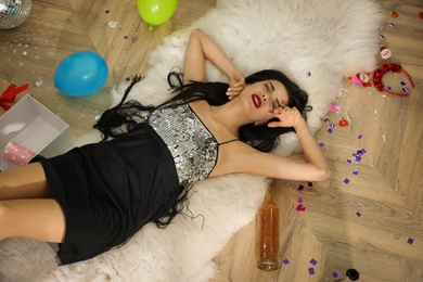 Photo of Woman sleeping on floor in messy room after New Year party, above view