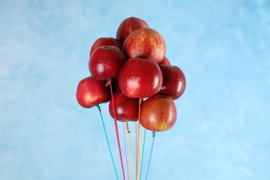 Photo of Ripe red apples hanging on light blue background