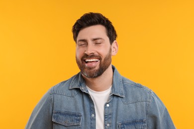 Photo of Portrait of handsome man laughing on yellow background