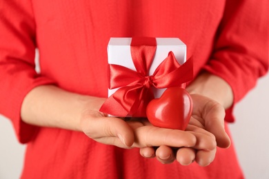 Photo of Woman holding gift box and red heart, closeup. Valentine's Day celebration
