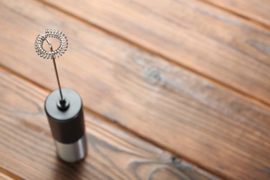 Black milk frother wand on wooden table. Space for text