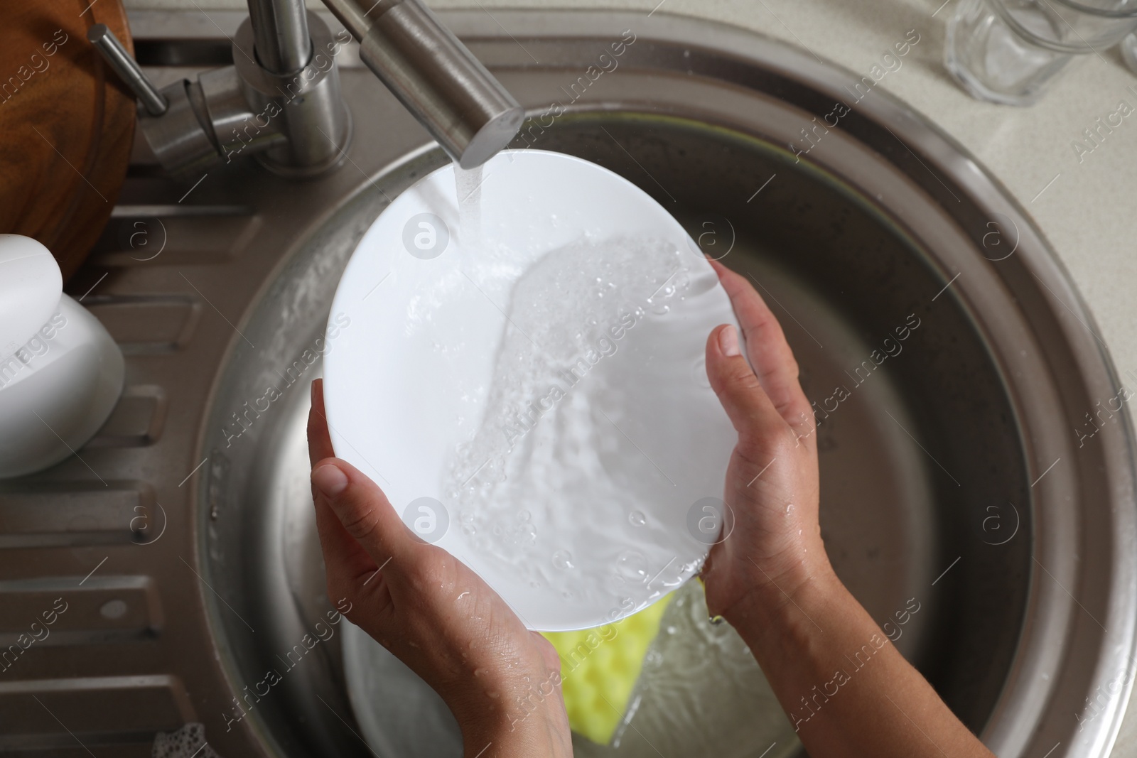 Photo of Woman washing plate in kitchen sink, above view