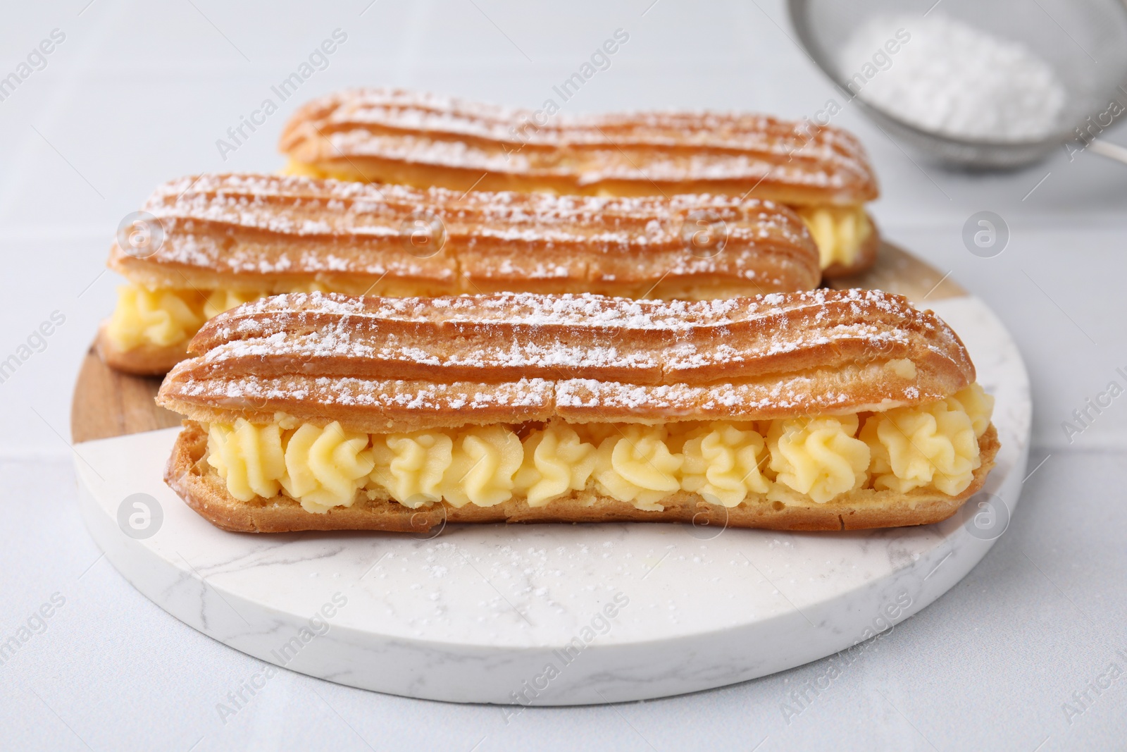 Photo of Delicious eclairs filled with cream on white table