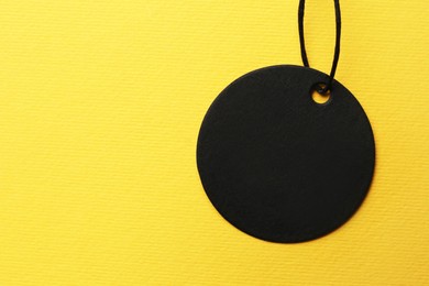 Photo of Circle shaped tag with space for text on yellow background, top view