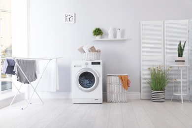 Photo of Laundry room interior with washing machine near wall