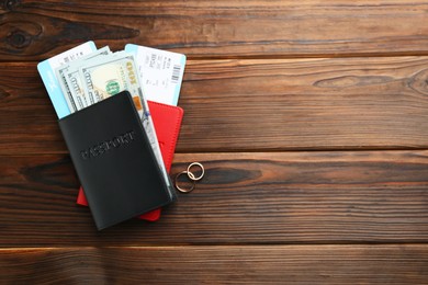 Photo of Honeymoon concept. Two golden rings, passports, money and tickets on wooden table, top view. Space for text