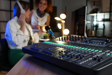 Photo of Women working in modern radio studio, focus on professional mixing console
