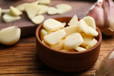 Fresh chopped garlic in bowl on wooden table, closeup. Organic product