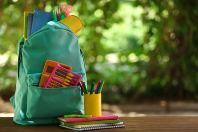 Color backpack and school stationery on table against blurred background, space for text