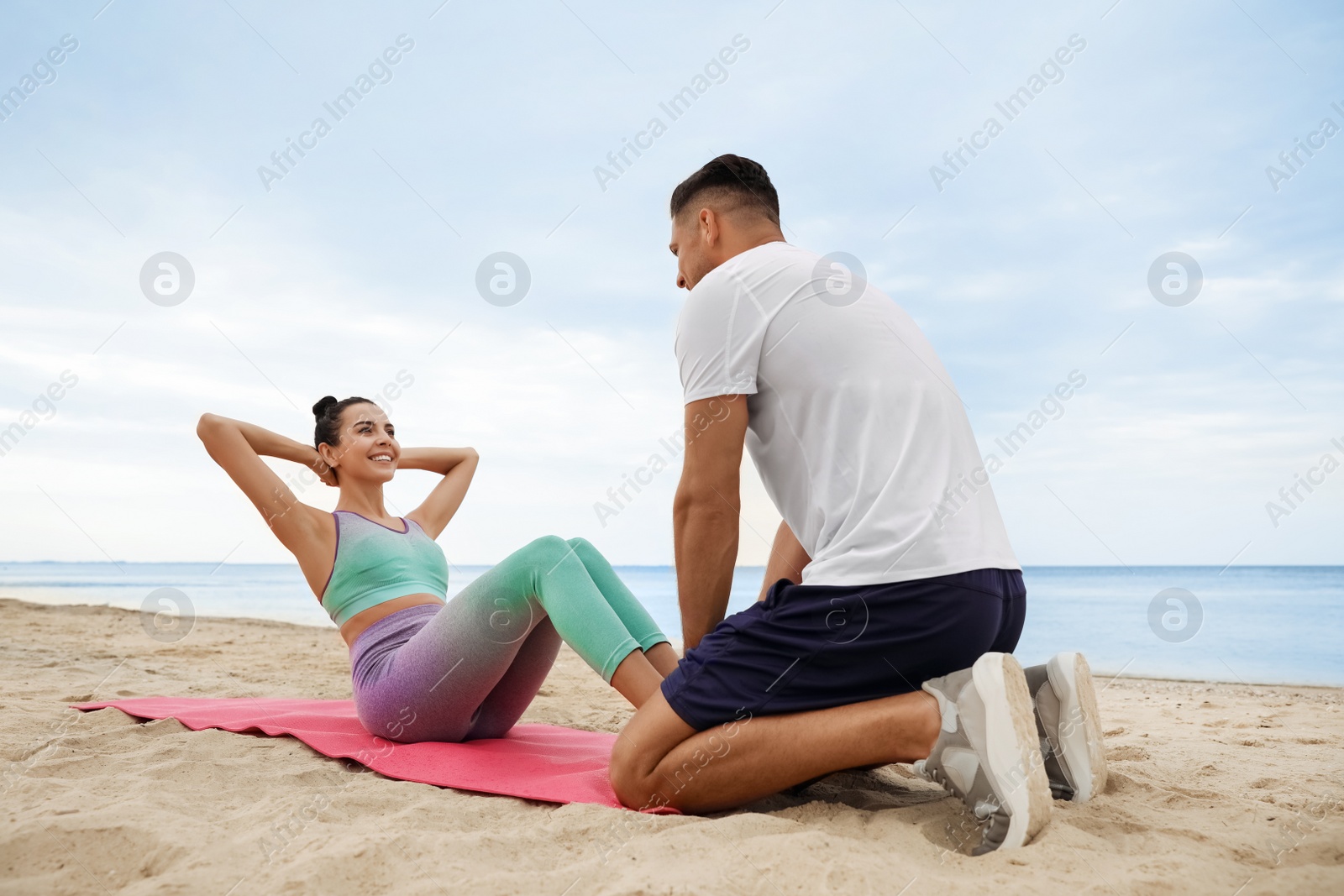 Photo of Couple doing exercise together on beach. Body training