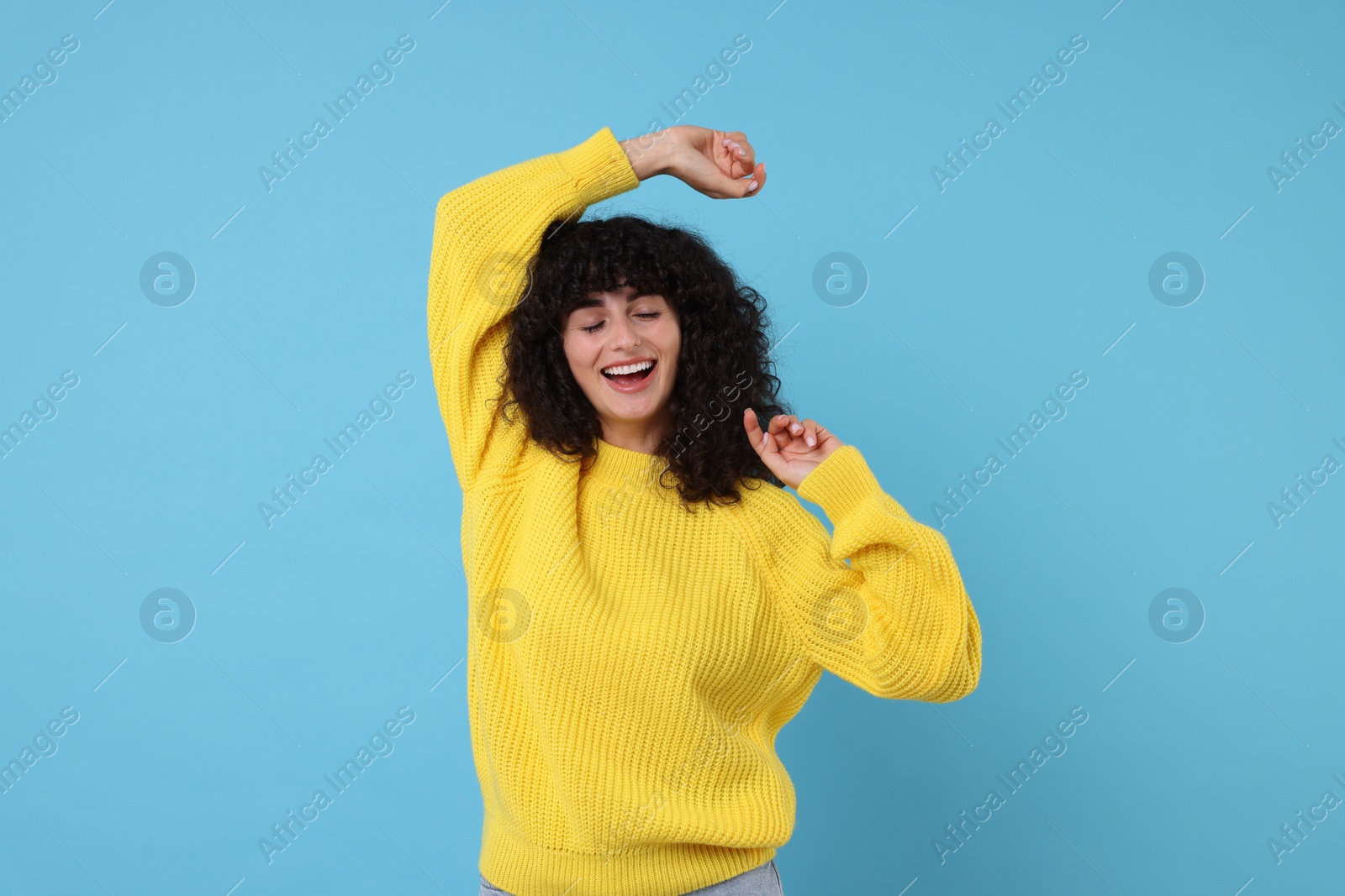 Photo of Happy young woman in stylish yellow sweater on light blue background