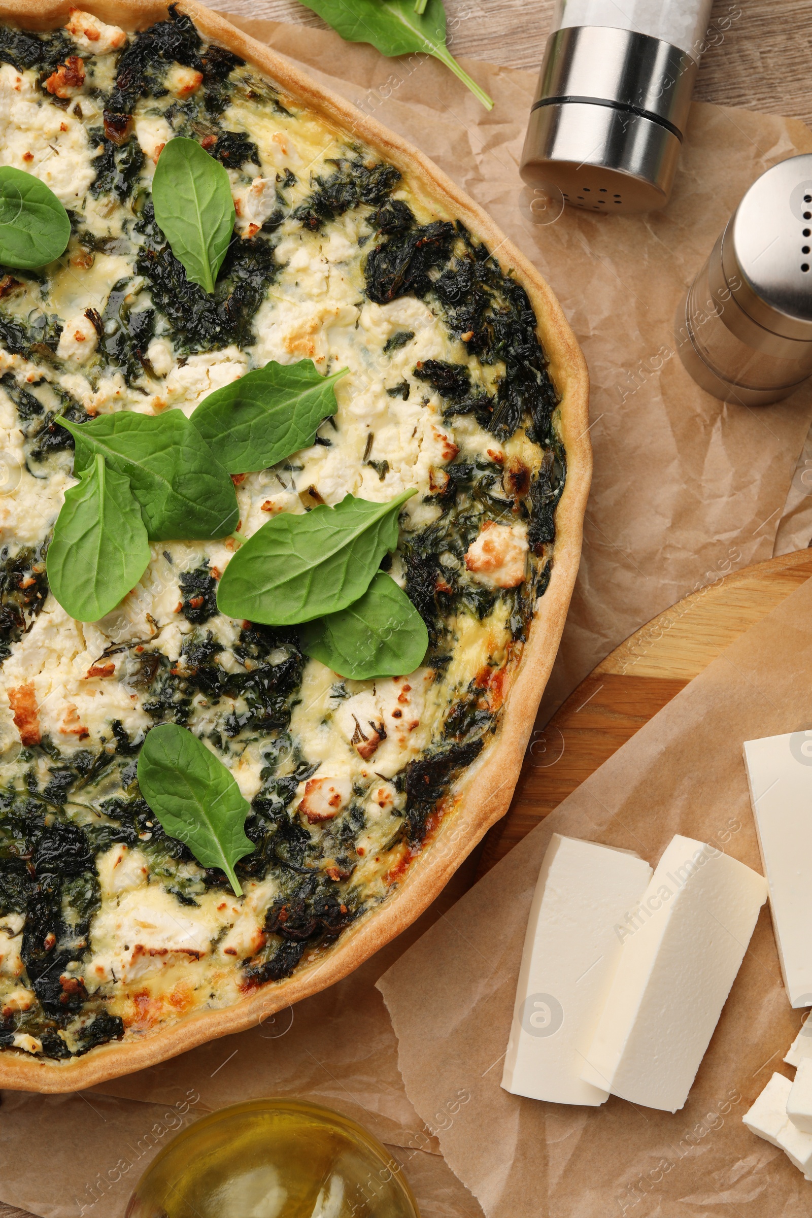 Photo of Delicious homemade spinach quiche and ingredients on table, flat lay