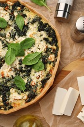 Delicious homemade spinach quiche and ingredients on table, flat lay