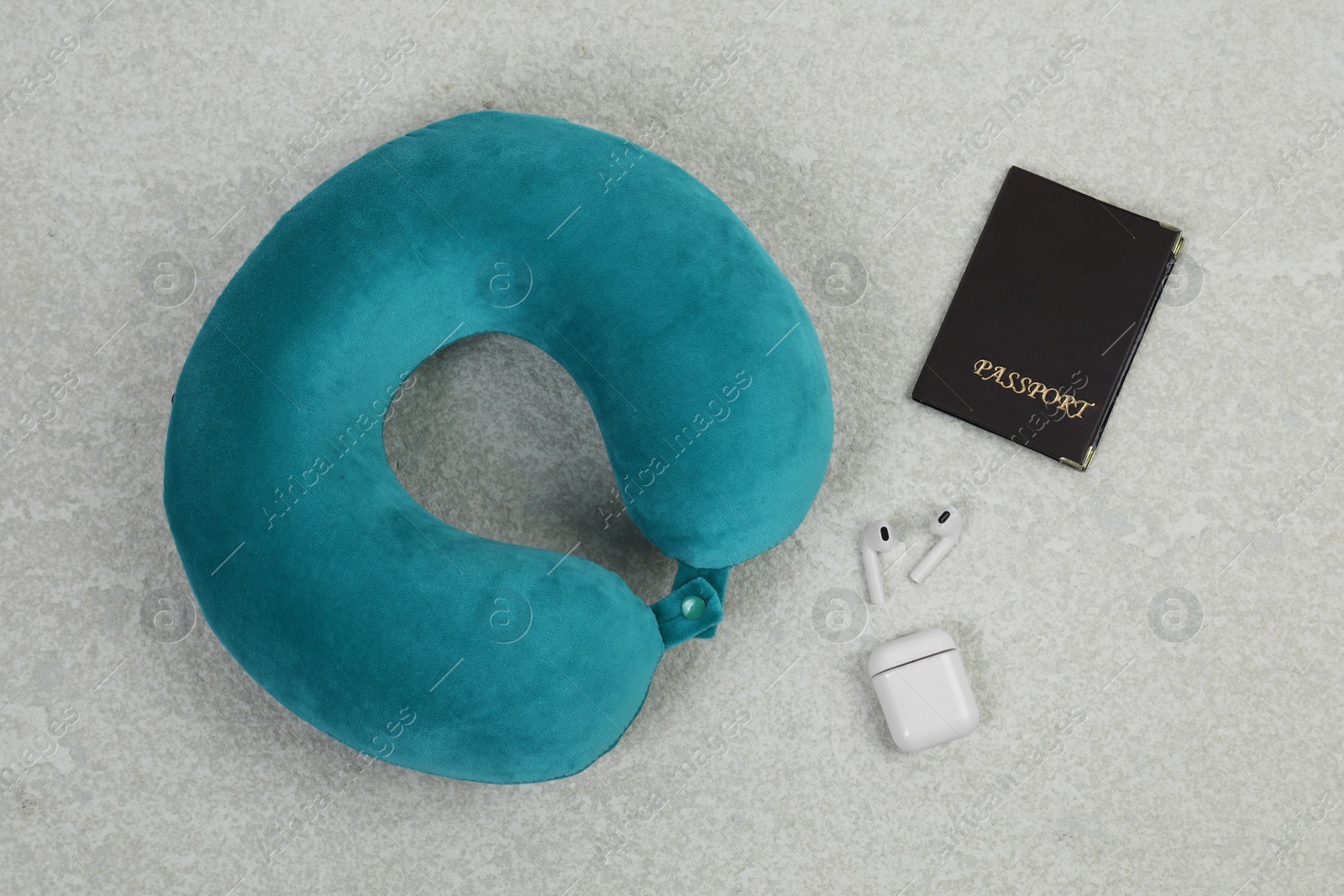 Photo of Soft travel pillow, passport and earphones on grey textured background, flat lay