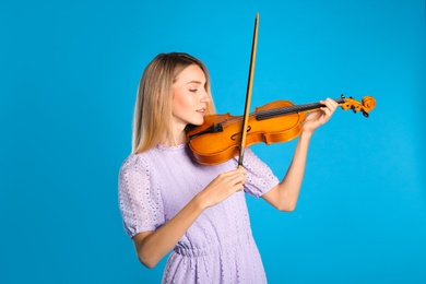 Photo of Beautiful woman playing violin on blue background