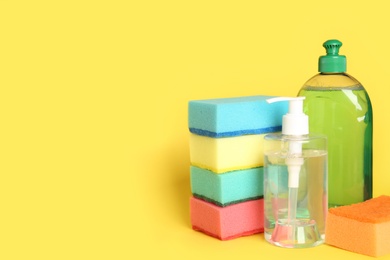 Photo of Detergents and sponges on yellow background, space for text