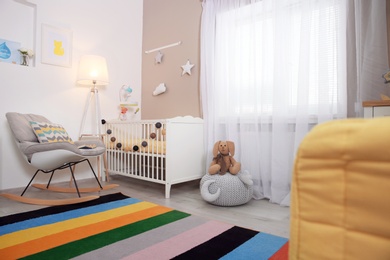 Photo of Cozy baby room interior with crib and rocking chair