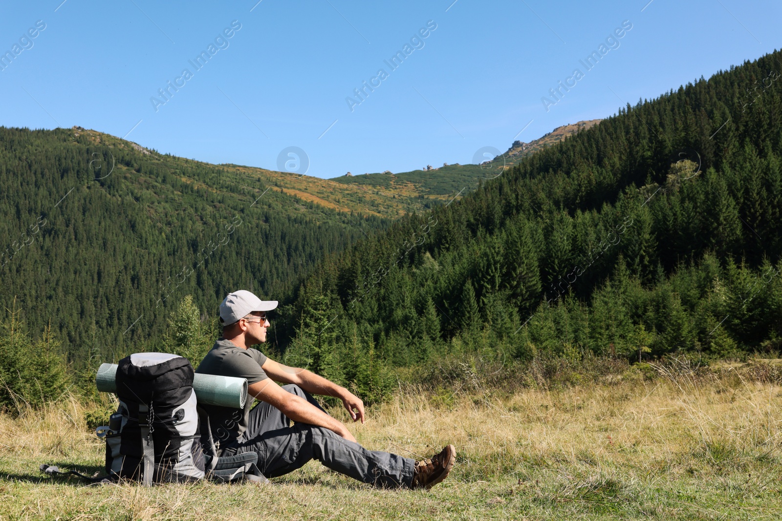 Photo of Tourist with backpack in mountains on sunny day. Space for text