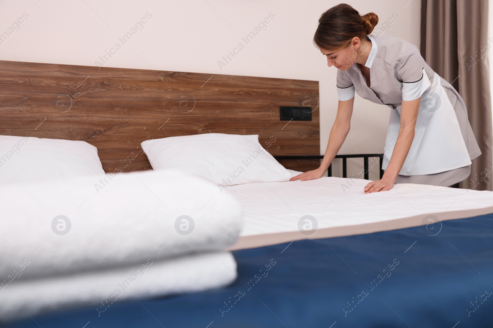 Photo of Beautiful chambermaid making bed in hotel room