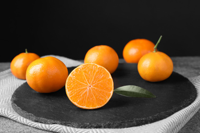 Photo of Fresh ripe juicy tangerines on slate board